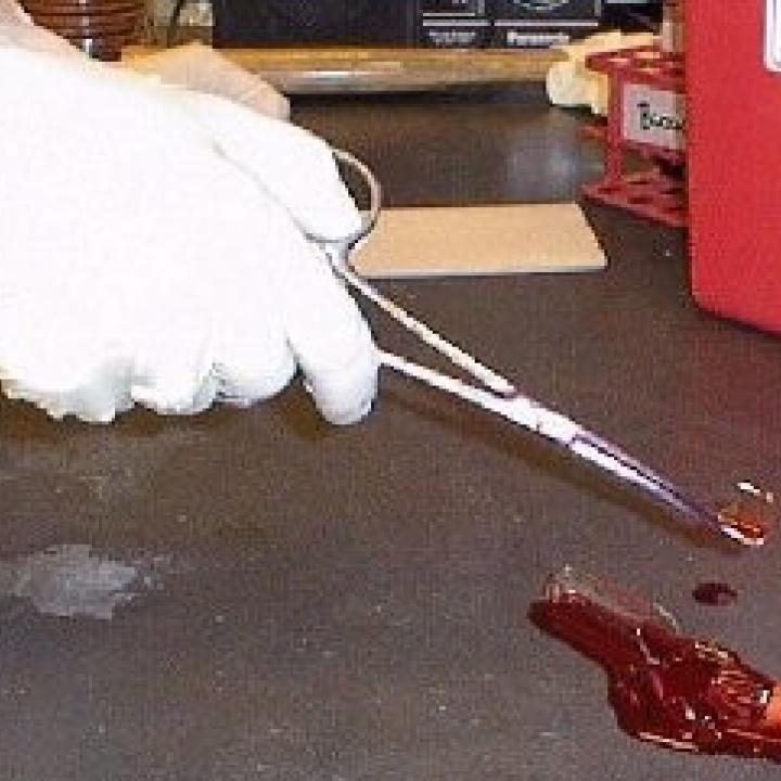 Image of forceps being used to pick up sharps